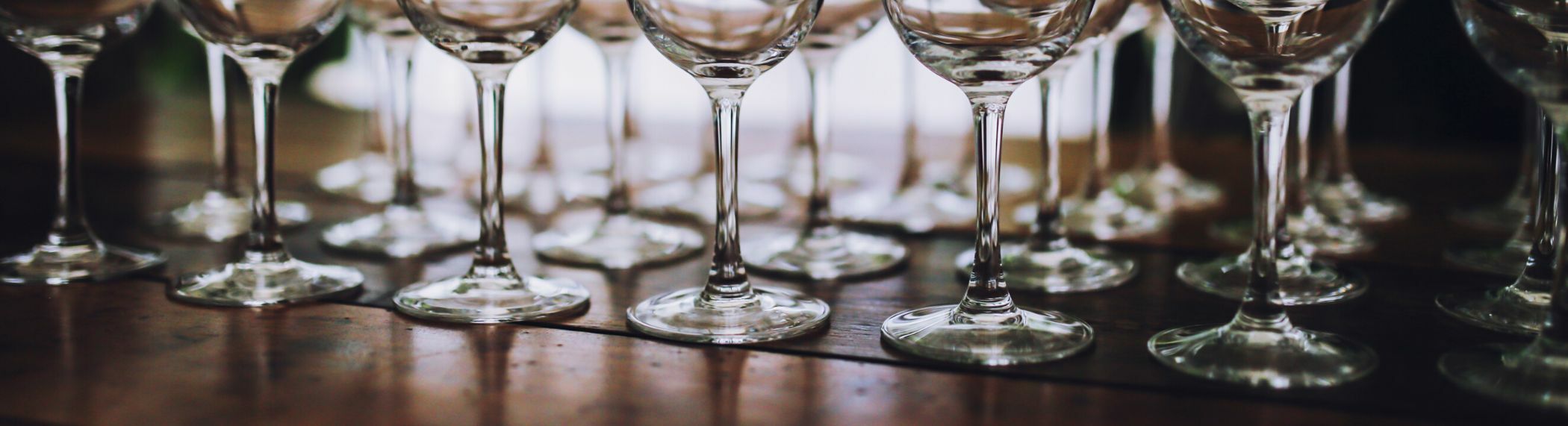 wine glasses lined up on a wooden bar